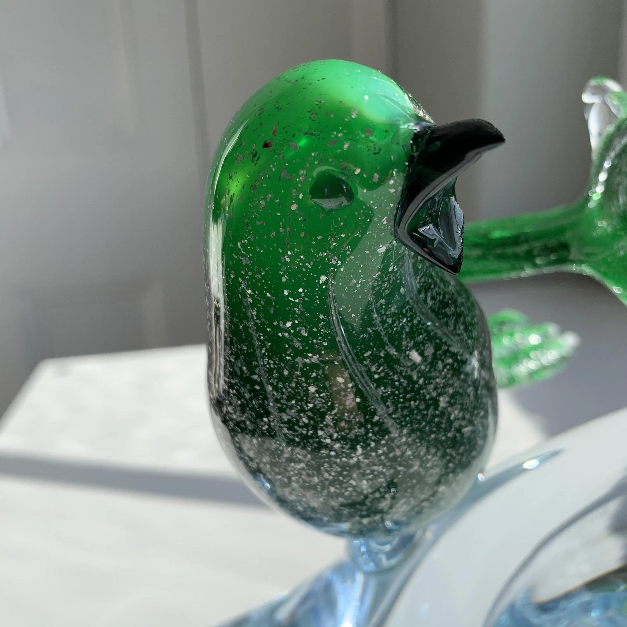 Green murano glass birds on a low branch